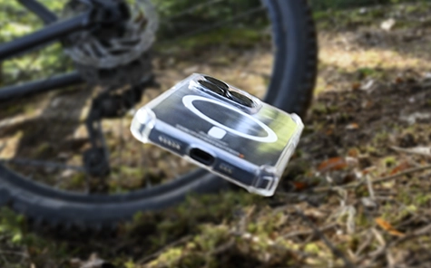 Smartphone na capa do celular cai da bicicleta no chão da floresta.